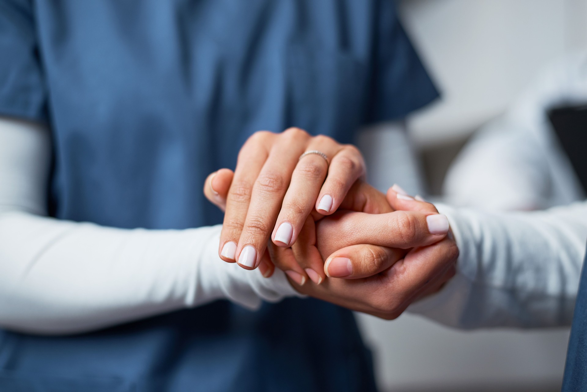 Compassionate Nurse Offering Comfort by Connecting Hands at a Healthcare Facility